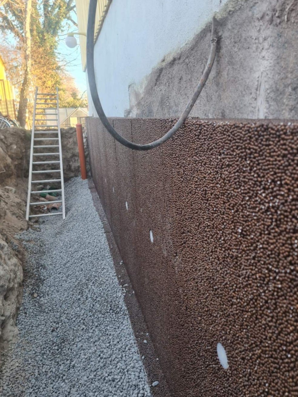 Dräneringsplatta monterad mot grunden och makadambädd i schaktet